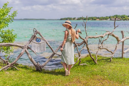Female tourist in a turquoise dress standing on a wooden pier over the turquoise waters of Bacalar Lake, Mexico. Peaceful tropical travel destination concept.