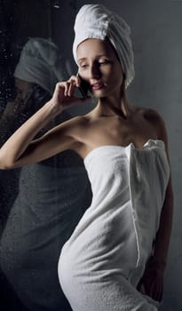Slim girl in white towel on her head cropped shot against gray wall