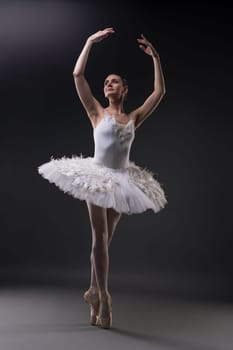 Ballerina in tutu and pointe dancing gracefully in dark room
