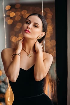 Beautiful elegant woman in black dress with festive makeup, beautiful photo with bokeh background.