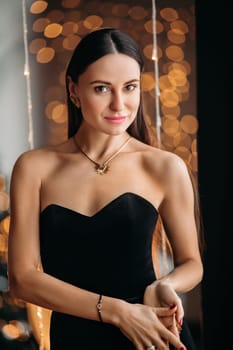 Beautiful elegant woman in black dress with festive makeup, beautiful photo with bokeh background.