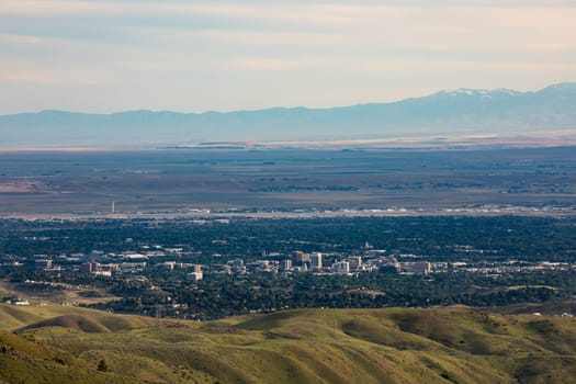 A breathtaking aerial view of Boise, showcasing the cityscape surrounded by lush greenery and distant mountains under a vast sky.