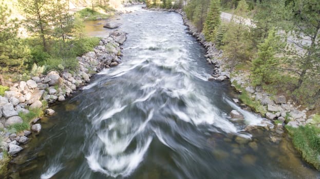 A picturesque view of a rushing river flowing through a tranquil forest. Surrounded by lush trees and rocky banks, the scene evokes peace and natural beauty.