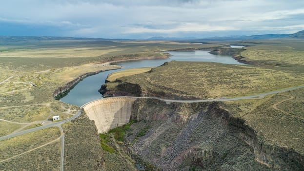Aerial panorama of a vast landscape showcasing a scenic dam surrounded by a winding river and expansive terrain. An ideal depiction of natural beauty and engineering.