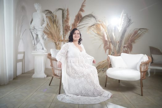 A woman in a delicate dress poses gracefully in a softly lit room, complemented by stylish decor and a calm ambiance.