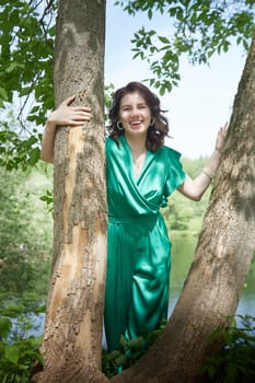 Portrait of a happy girl in the park in summer. Holidays, rest, youth. A young girl with curly hair in a green park on a summer day