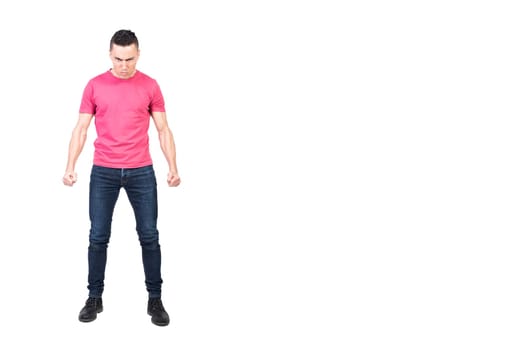 Full length angry male in jeans and pink t shirt clenching fists and looking at camera with frown while starting fight against white background