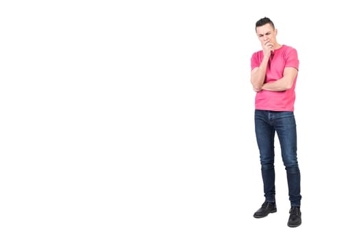 Full body of pensive male model in casual outfit touching chin while showing expression of confusion on white background