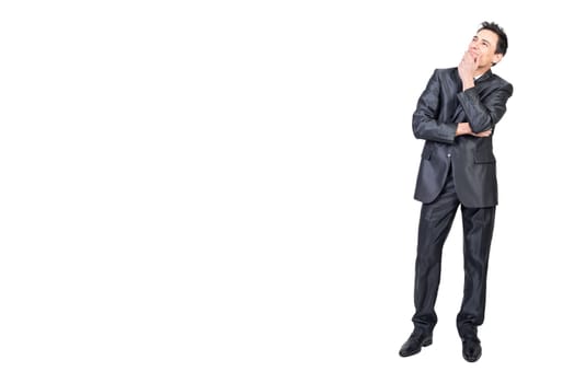 Full body of elegant young male manager with dark hair in classy suit touching chin and looking away dreamily in white studio