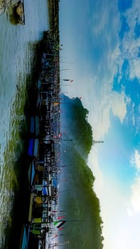 A large group of boats are floating on a lake. The sky is blue with some clouds