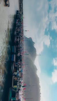 A large group of boats are floating on a lake. The sky is blue with some clouds