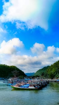 A large group of boats are floating on a lake. The sky is blue with some clouds