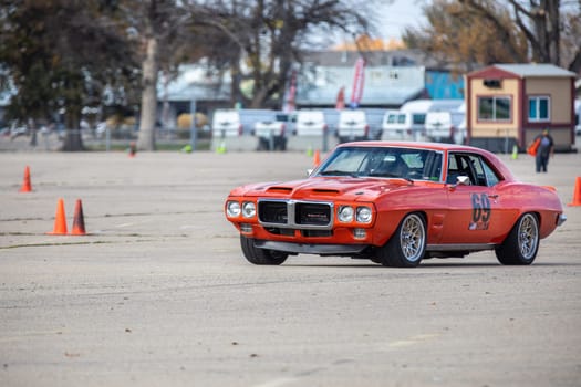 Boise, Idaho - October 31, 2021: A striking red vintage muscle car navigates through an asphalt race track capturing the excitement and speed of a classic auto racing