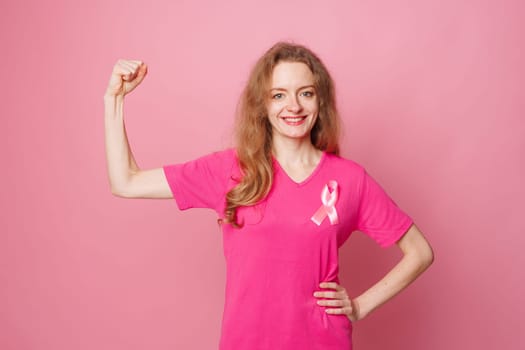 Young woman with pink ribbons showing muscles on color background. Breast cancer awareness concept, Breast cancer awareness concept
