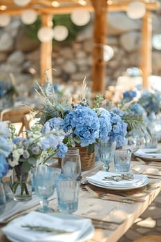 The wedding reception table is elegantly decorated with a mix of blue and white flowers in vases, complemented by matching glasses and tableware for a stunning interior design