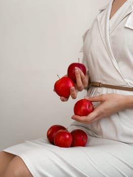 Elegant woman in white dress holding fresh red apples.