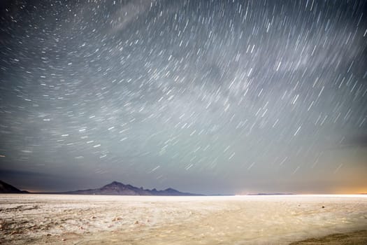 Mesmerizing star trails in the night sky over a serene desert landscape, showcasing the vastness and tranquility of nature. Captures the essence of the universe in motion.