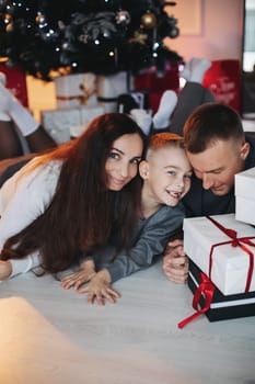 A family around the Christmas tree in the new year, a holiday with family,a beautiful happy stylish family.