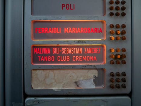 Cremona, Lombardy, Italy October 15th 2024 Close up of an old, illuminated intercom displaying names like maria rosaria ferraioli and tango club cremona