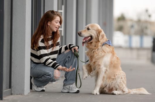 Teen Girl With Golden Retriever Near Store Plays In Spring