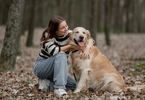 Teenage Girl Sits With Golden Retriever In Park During Autumn
