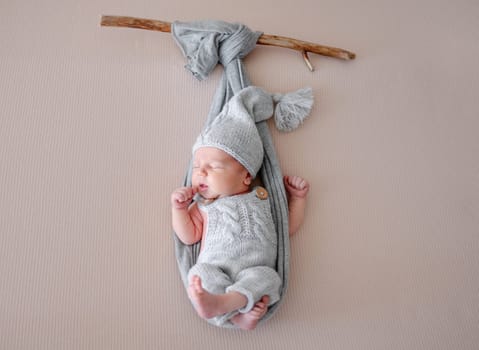 Newborn Baby Sleeps In Hammock Imitation On Branch During Photo Session