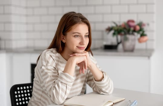 Thoughtful Teenage Girl Smiles At Home At The Table