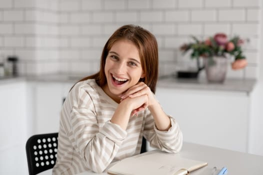 Girl Joyfully Smiles Sitting At Home Table