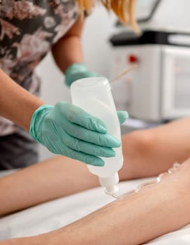 Master Of Laser Hair Removal Applies Gel To Girl'S Leg In Close-Up View