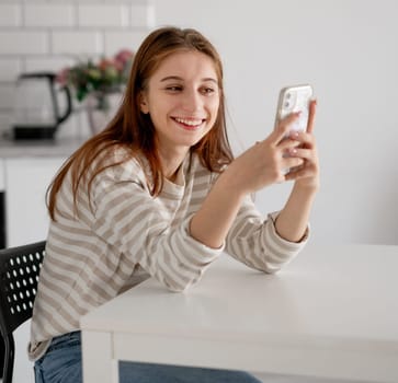 Cheerful Girl Talks On Phone At Home In Kitchen