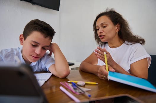 A young student and a teacher engaged in a focused tutoring session. The teacher explains concepts while the student listens intently, fostering a supportive learning environment.