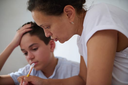 A mother guides her son through a challenging homework session. They are focused and concerned, embodying parental support and educational dedication.