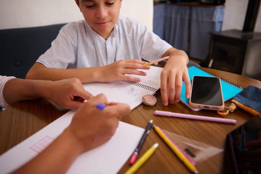 A child gets homework help from a parent, surrounded by school supplies at a cozy home setting. It's a moment of learning and support, illustrating family bonding and education at home.