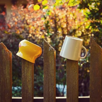Mugs on the fence. Autumn background with nature and sunset.