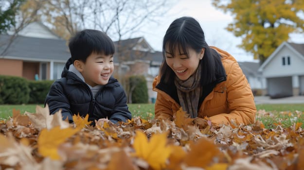 Mother and son are laughing and playing in a pile of orange autumn leaves in the suburbs