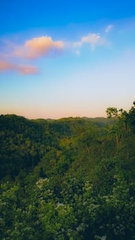 A tranquil mountain valley with lush greenery and a beautiful sunrise. The early morning light casts soft pastel colors over the landscape, creating a serene and peaceful ambiance.