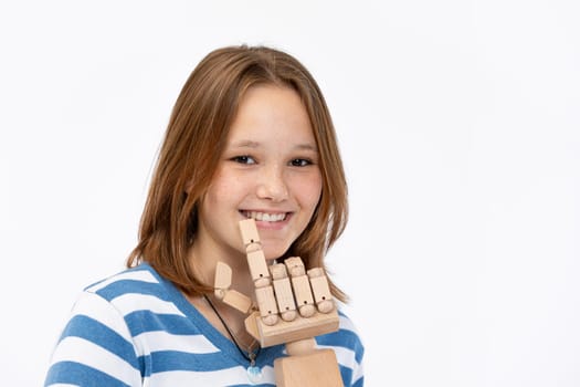 A cheerful girl shows a joyful gesture with a crafted wooden hand, embodying creativity and fun in expression