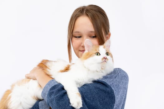 A girl joyfully holds a fluffy ginger cat against a bright background, showcasing their beautiful bond