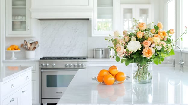 Bouquet of peach and white roses and a bowl of oranges are sitting on a white marble countertop in a modern kitchen