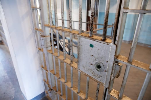 A rusty prison cell door in an abandoned correctional facility, capturing the essence of confinement and freedom. The image evokes a sense of desolation and mystery.
