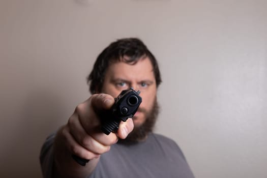 A focused man pointing a gun directly at the camera, emphasizing intensity and confrontation. The close-up captures a sense of urgency and tension.