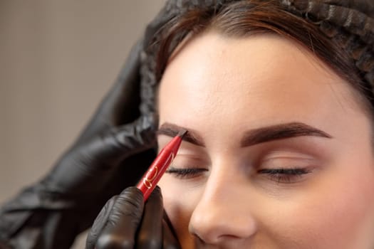 The specialist carefully sketches lines for a lasting and attractive makeup look.