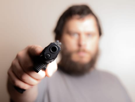 Close-up image of a man pointing a gun directly at the viewer, emphasizing intensity and focus. Perfect for themes of action, crime, or suspense in media projects.