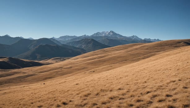 A tranquil landscape reveals rolling golden grasslands contrasting with majestic mountain peaks under a brilliant blue sky, evoking a sense of peace and solitude.