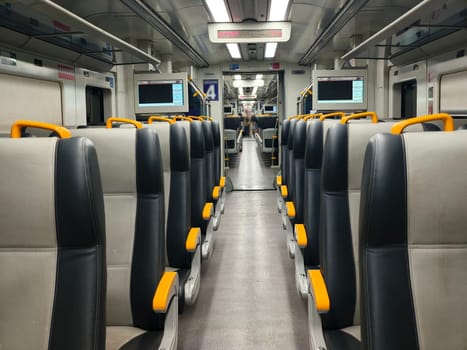 an empty train carriage with rows of seats and a clear view down the aisle.