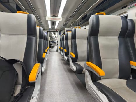 an empty train carriage with rows of seats and a clear view down the aisle.