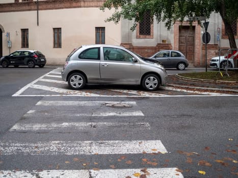 Cremona, Lombardy, Italy October 15th 2024 A silver car parked illegally and blocking a pedestrian crossing in an urban area, creating a safety hazard for pedestrians