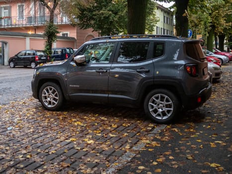 Cremona, Lombardy, Italy October 15th 2024 Modern gray jeep renegade parked on a cobblestone street covered with fallen autumn leaves
