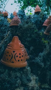 Decorative terracotta pots placed on rugged, rocky terrain juxtaposed with lush green foliage, creating a rustic and artistic outdoor scene. Ideal for themes of nature, craftsmanship, and aesthetics.