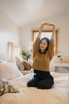 Beautiful young woman stretching in cozy bed after waking up.
